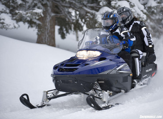 2 people on a Polaris Trail Touring Snowmobile.